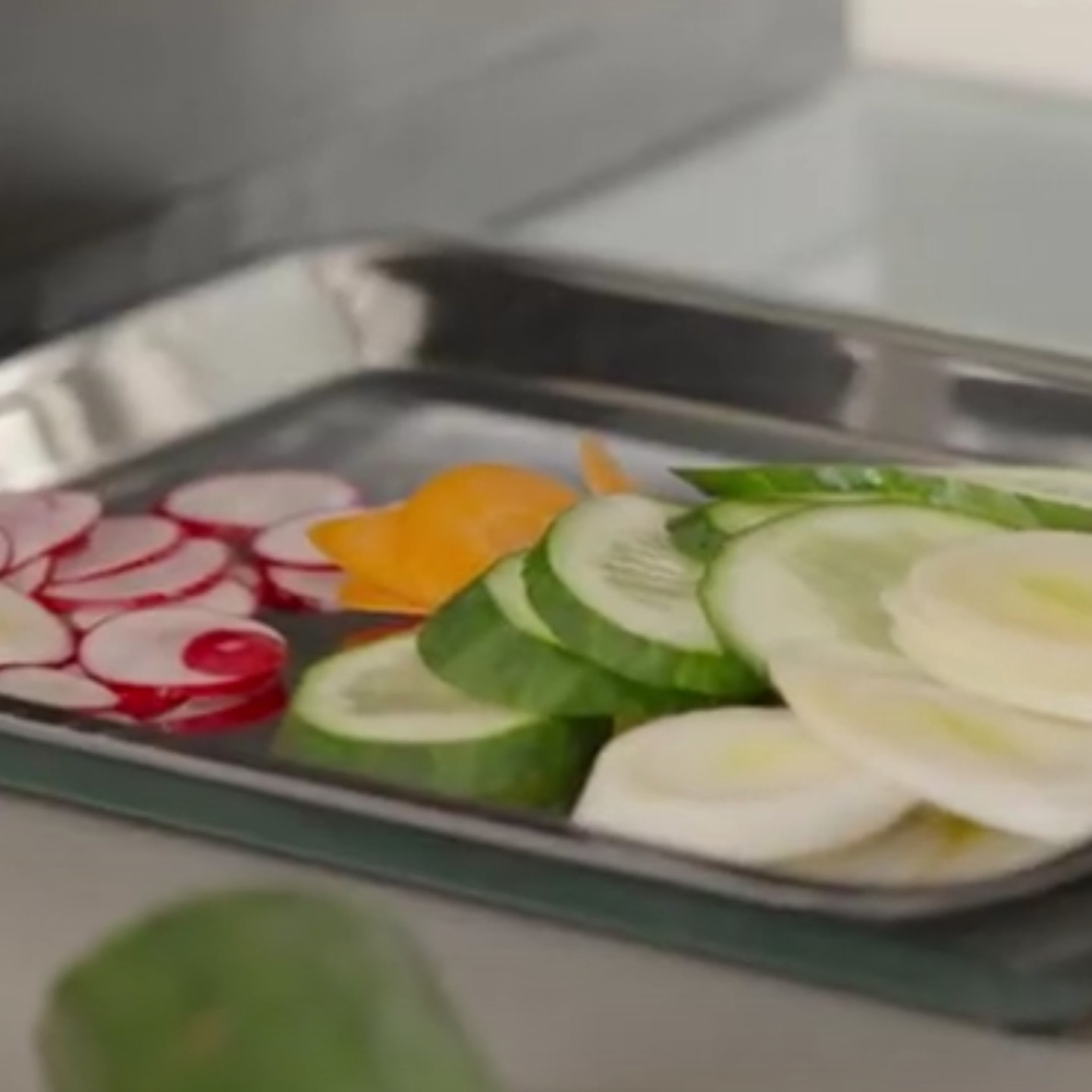 Gemüseplatte mit Radieschen, Gurken und Karotten, in Scheiben geschnitten