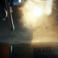 Steam jet hits a surface with water droplets and the GRAEF logo.