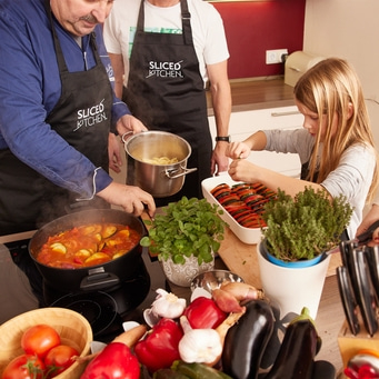 Familie kocht gemeinsam in der Küche, Gemüse und Kochutensilien.