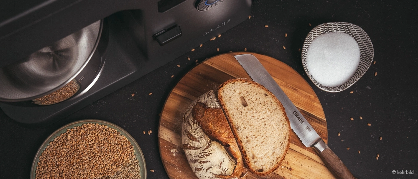 Ein Graef Brotschneidemaschine, Brot, Weizen und Salz auf einem Tisch.