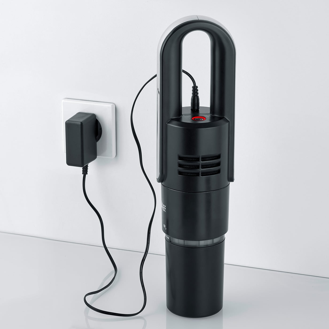 Schwarzer Staubsauger mit Ladegerät an der Wand, bereit zum Aufladen.