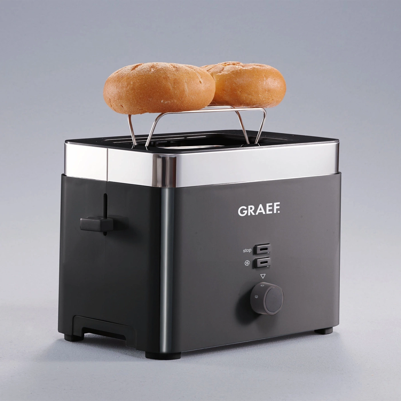 Graef Toaster mit Brötchenaufsatz und zwei Brötchen auf grauem Hintergrund