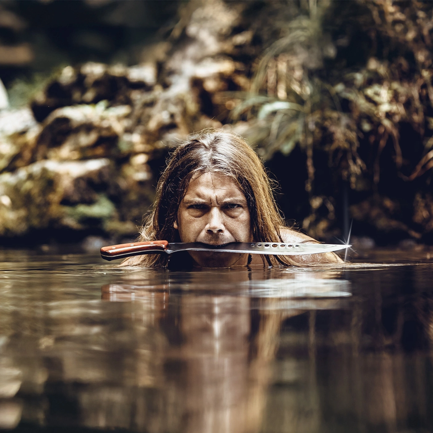 Man with knife in mouth in water