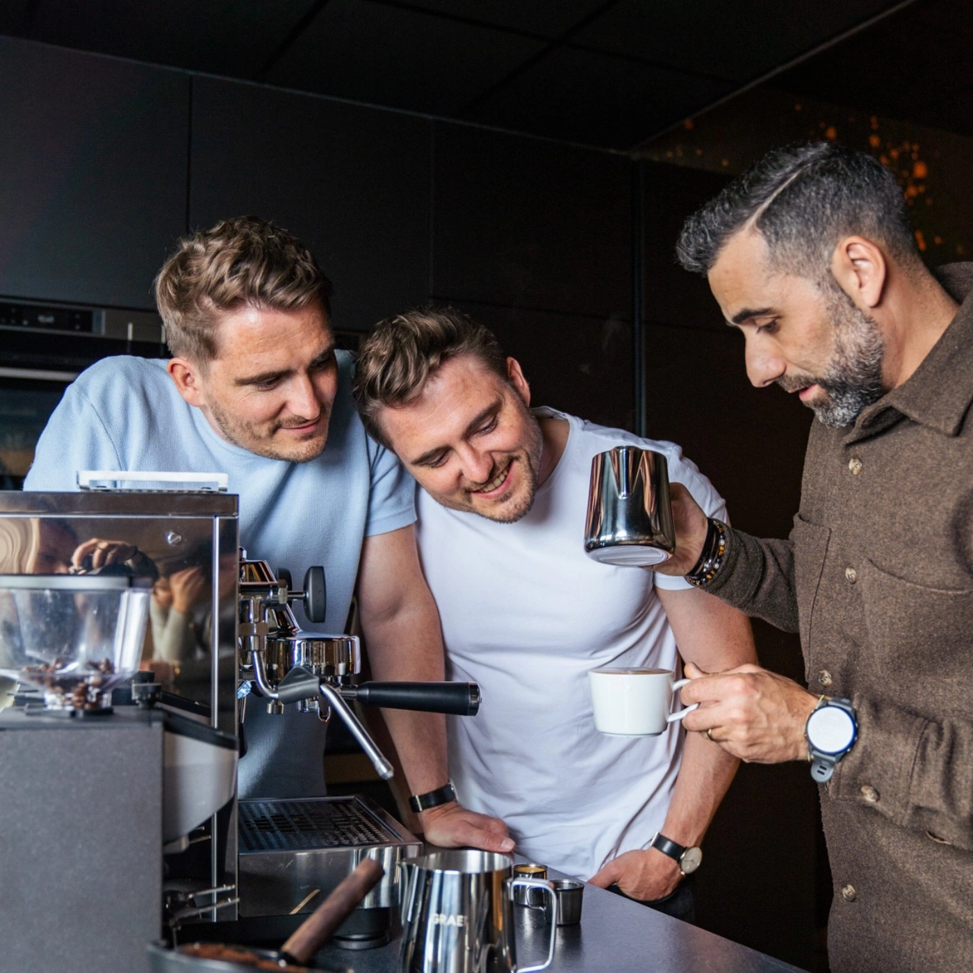 Drei Männer begutachten Kaffee, der mit einer Espressomaschine zubereitet wurde.