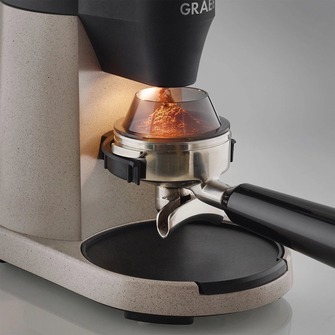 Kaffeemühle mit Kaffeepulver im Siebträger, Nahaufnahme, beleuchtet, grau