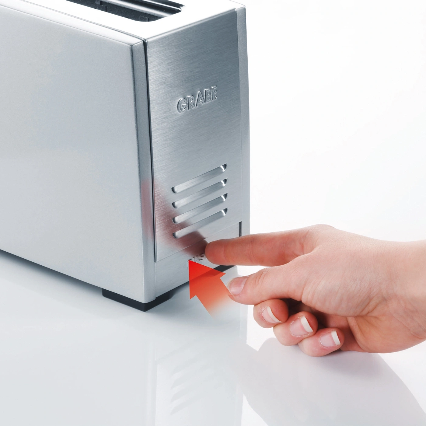 Silver toaster with hand pressing button, red arrow pointing towards it