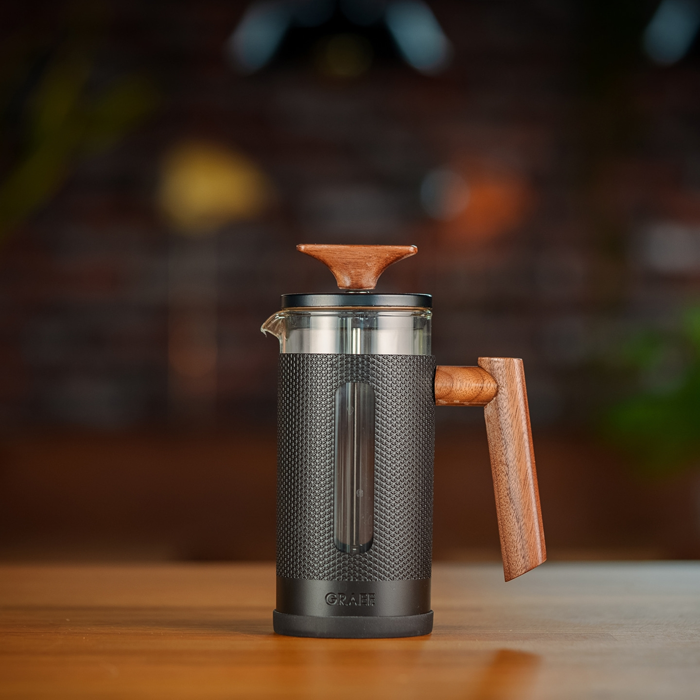 Close-up of a coffee press with wooden handle and lid on a wooden table.