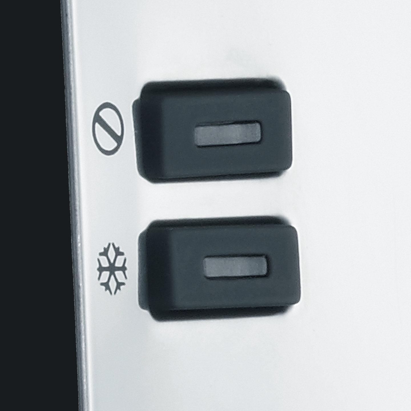 Zwei Knöpfe mit Symbolen, die auf einer Metalloberfläche angebracht sind.