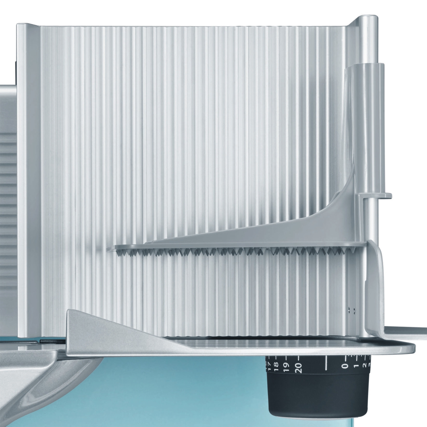 Close-up of a silver meat slicer with adjustment dial and serrated edges