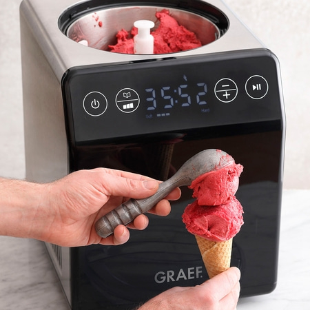 Eismaschine mit Eiscreme, die in einen Waffelkegel geschöpft wird.