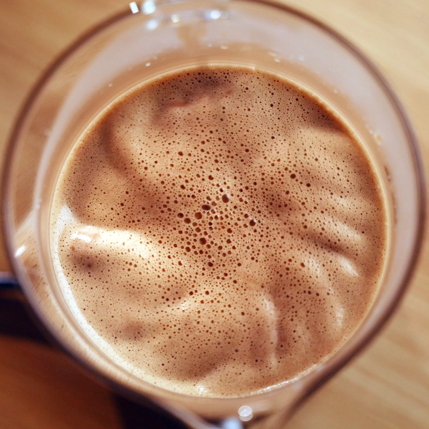 Eine Nahaufnahme von schaumigem Kakao in einem Glas.