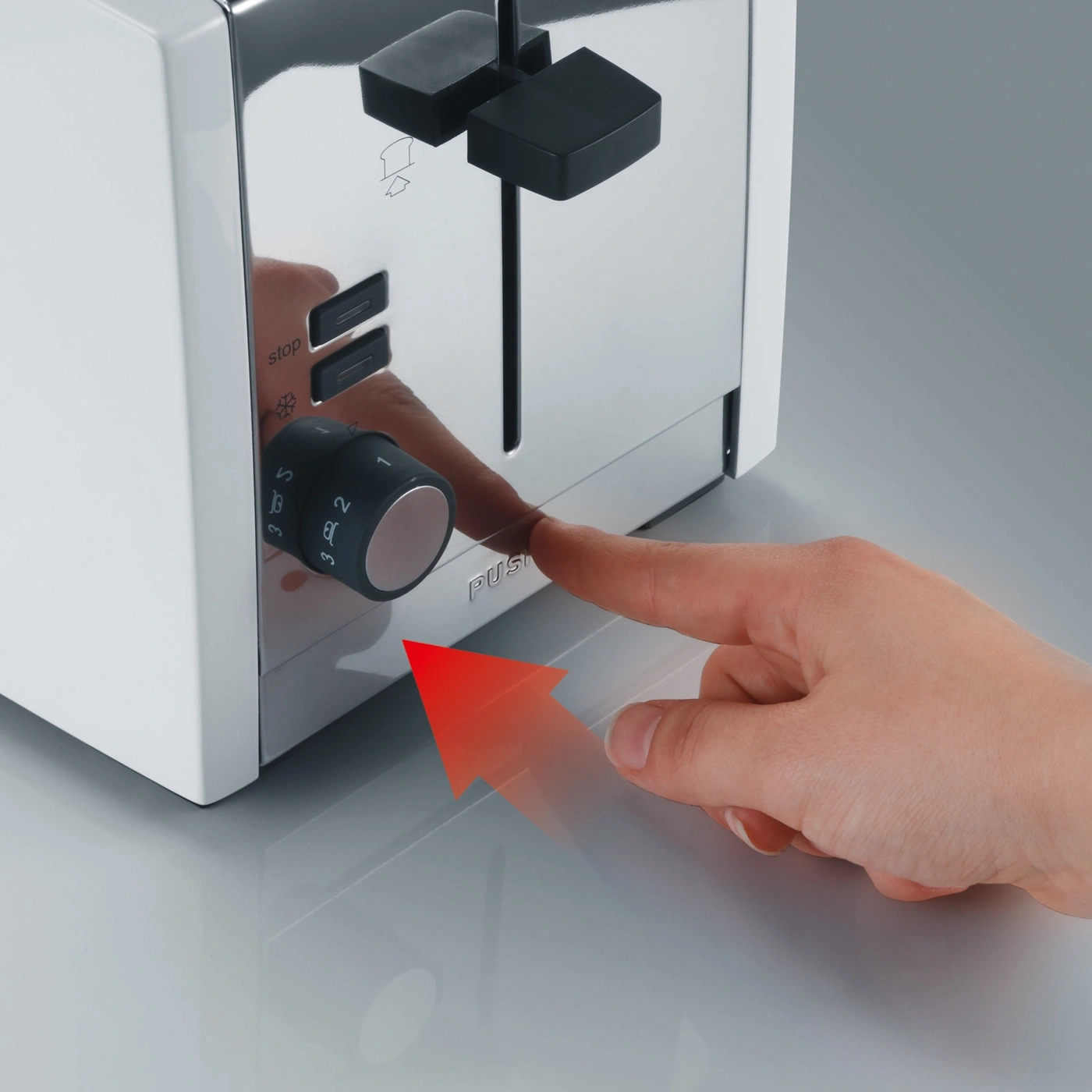 Ein Finger drückt einen Knopf auf einem Toaster, um ihn zu bedienen.