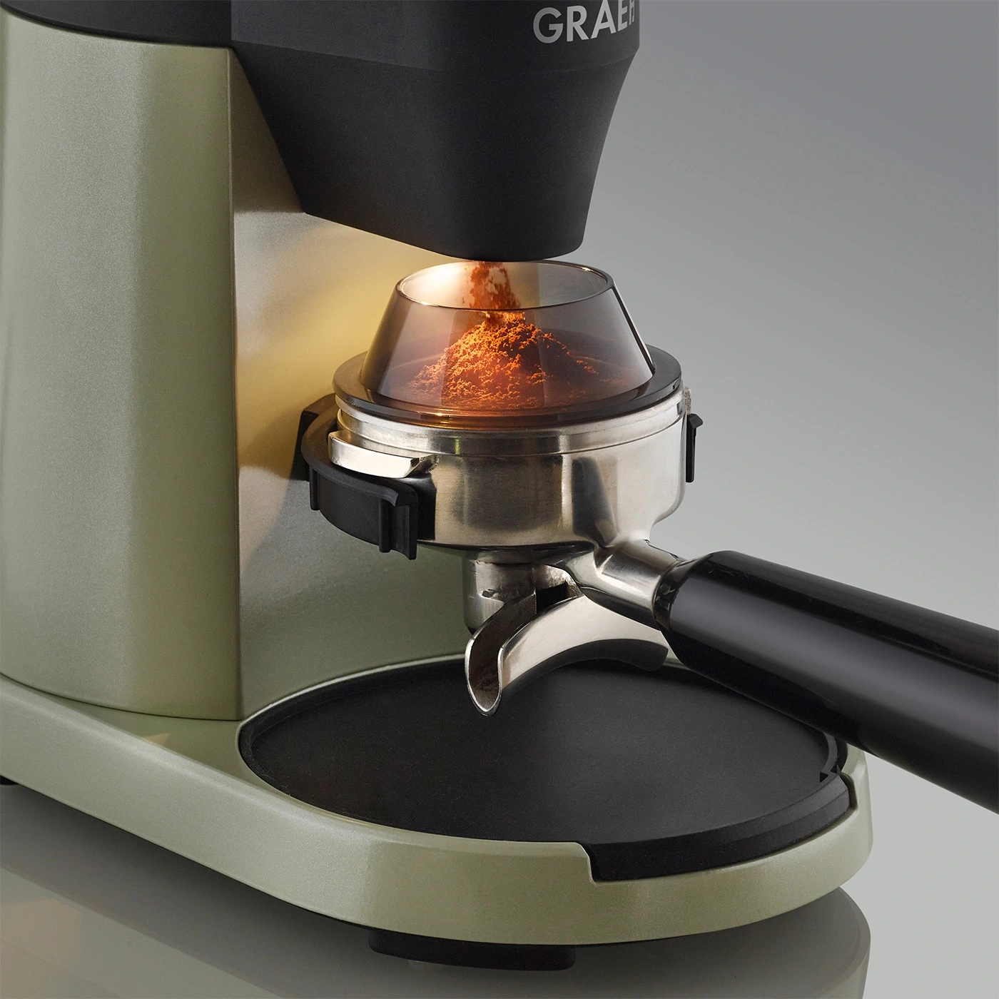 Nahaufnahme einer Kaffeemühle mit frisch gemahlenem Kaffee in einem Siebträger.