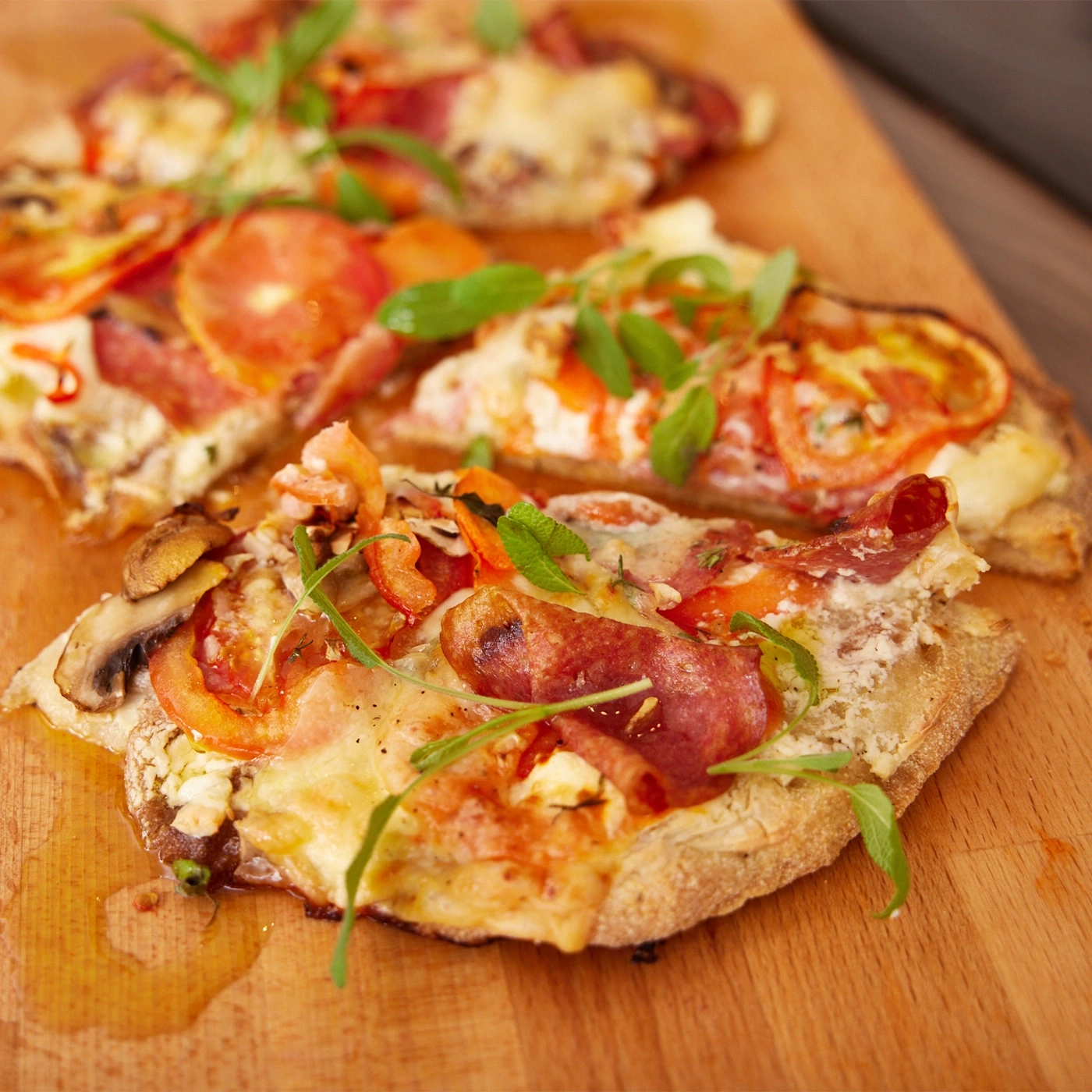 Close-up of pizza with tomatoes, cheese, and herbs on a wooden board