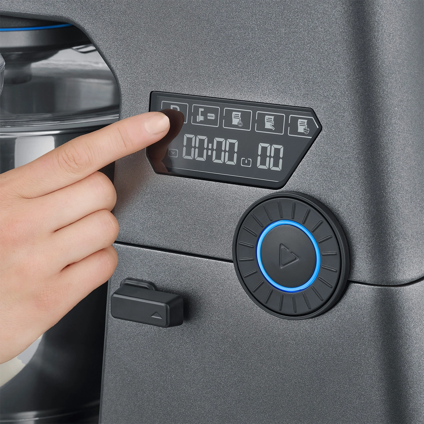 Hand drückt Taste an Küchenmaschine. Digitalanzeige zeigt 00:00.00. Bedienfeld mit Symbolen.