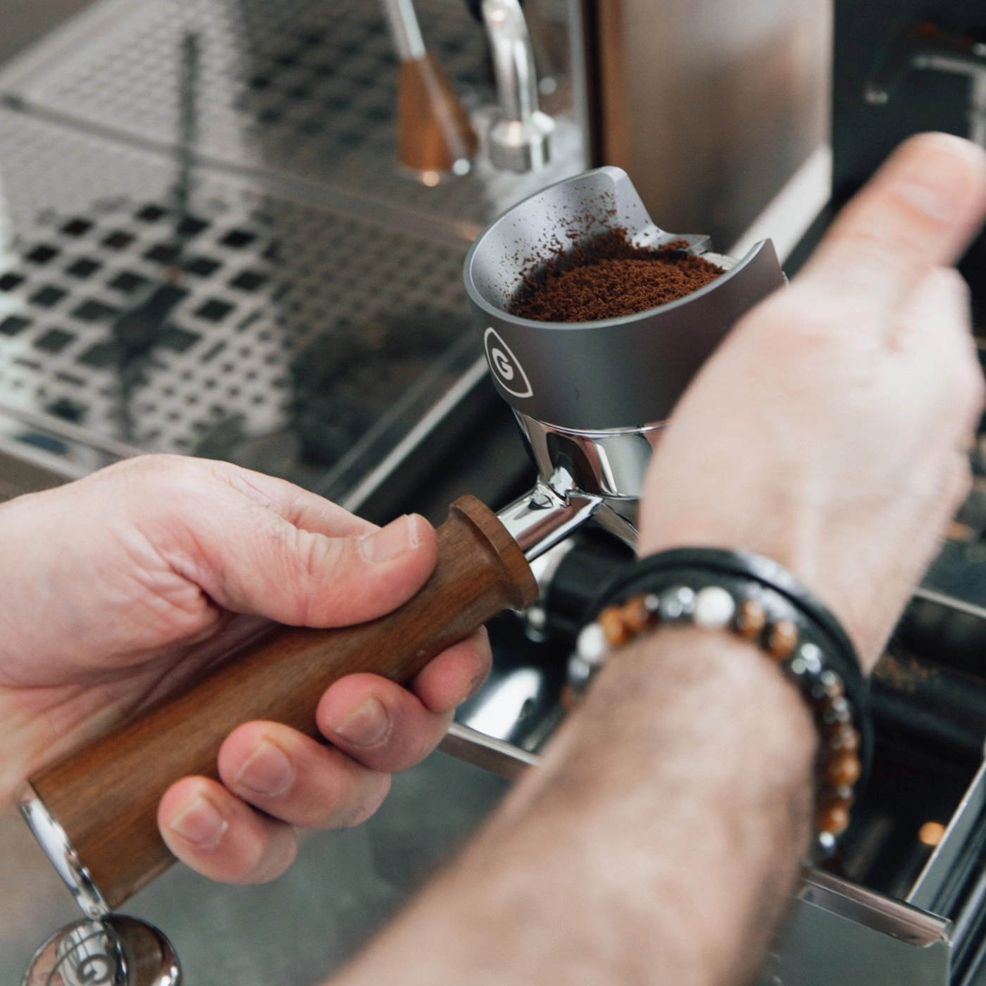 Hands holding a coffee filter with coffee grounds in a coffee machine.
