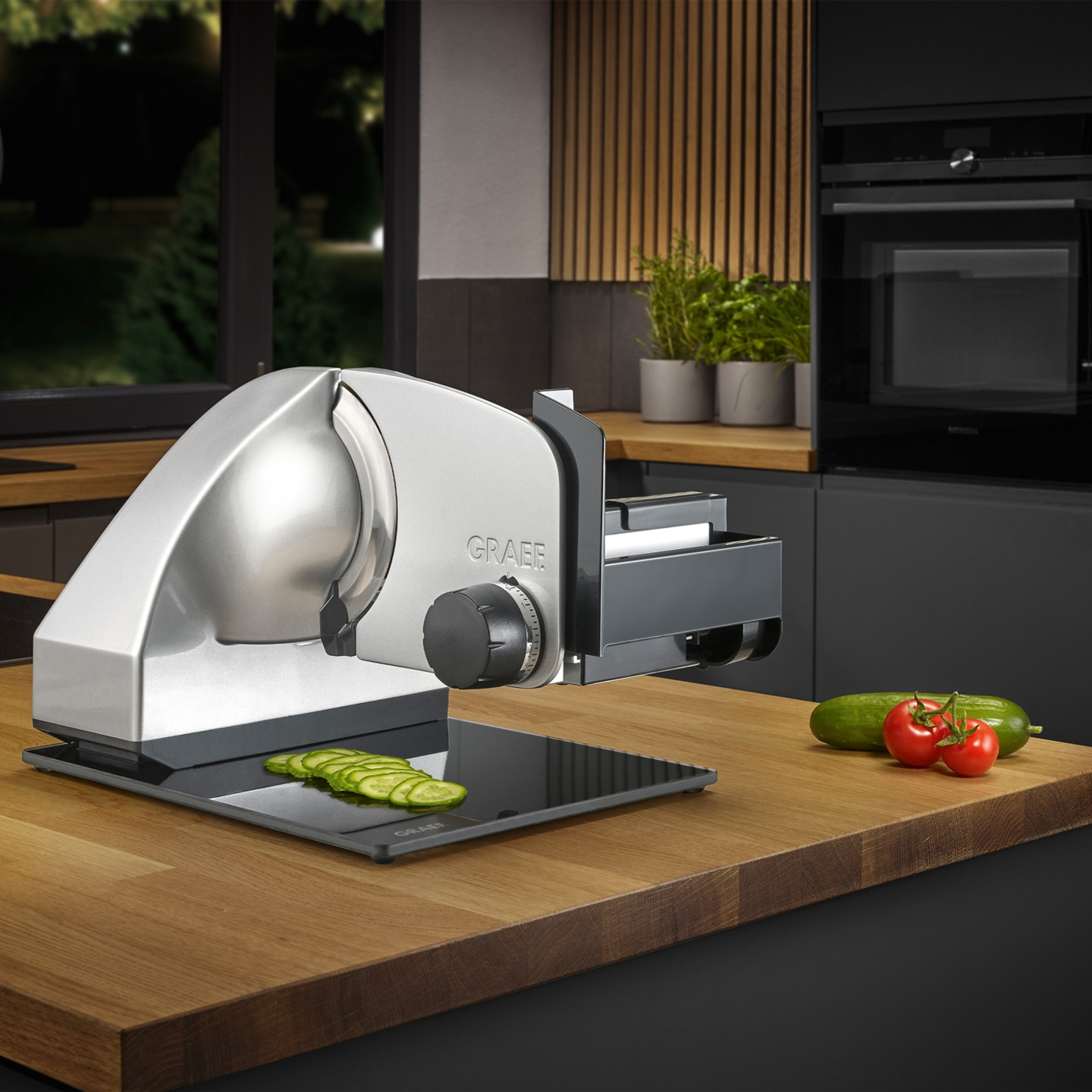 Elektrische Aufschnittmaschine mit Gemüse auf einer Holzoberfläche in einer Küche.