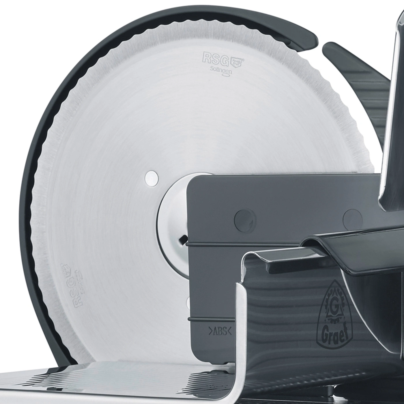 Close-up of a gray meat slicer with a serrated blade and a logo on it