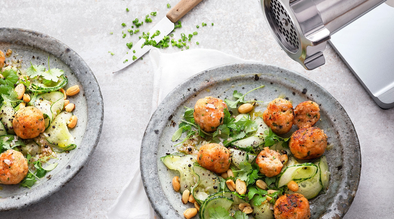 Fleischbällchen-Salat mit Erdnüssen und Gurken auf einem Teller, Nahaufnahme
