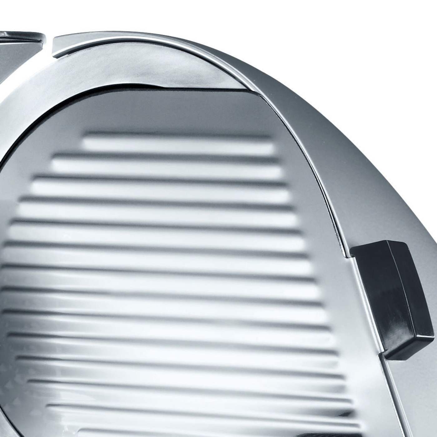 Close-up of a silver meat slicer with a black handle and a ridged surface