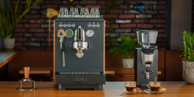 Espressomaschine und Kaffeemühle mit zwei Tassen Espresso auf einem Holztisch.