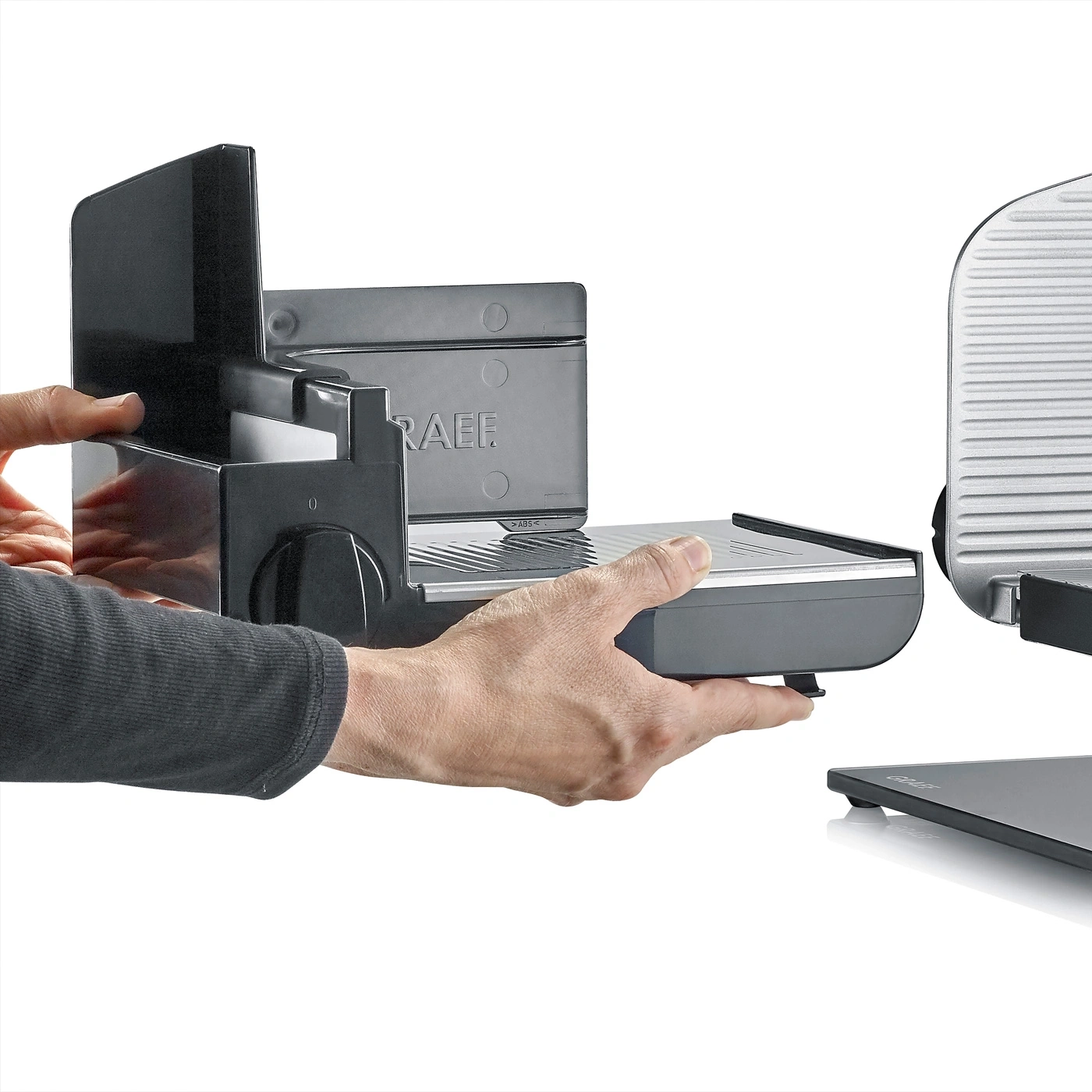 Graef slicer disassembled, hands holding parts, detail shot, gray