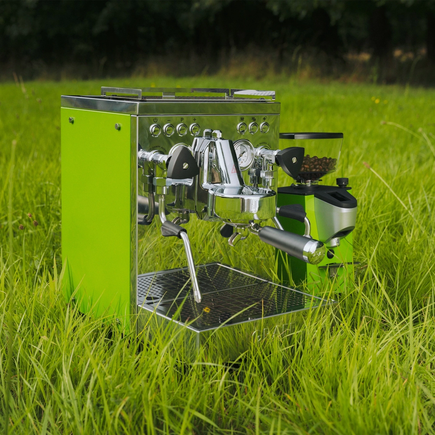 A green espresso machine with coffee grinder set on green grass.