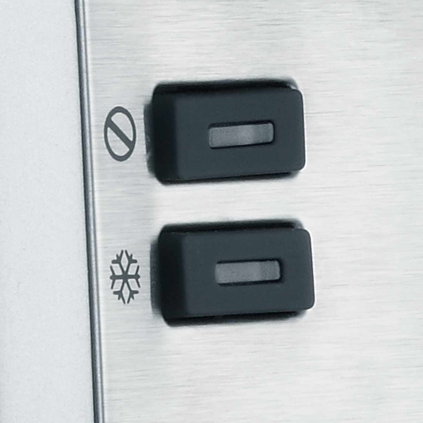 Zwei schwarze Knöpfe mit Symbolen auf einer Metalloberfläche.