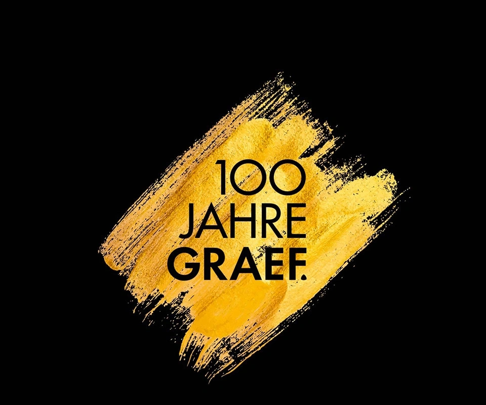Goldener Pinselstrich mit Text: 100 Jahre GRAEF auf schwarzem Hintergrund.