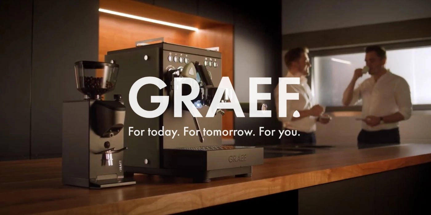 Coffee machine with two men drinking coffee, GRAEF brand advertisement.