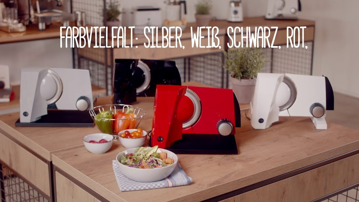 Gemüseschneider in verschiedenen Farben: Silber, Weiß, Schwarz, Rot. Auf Holztisch.