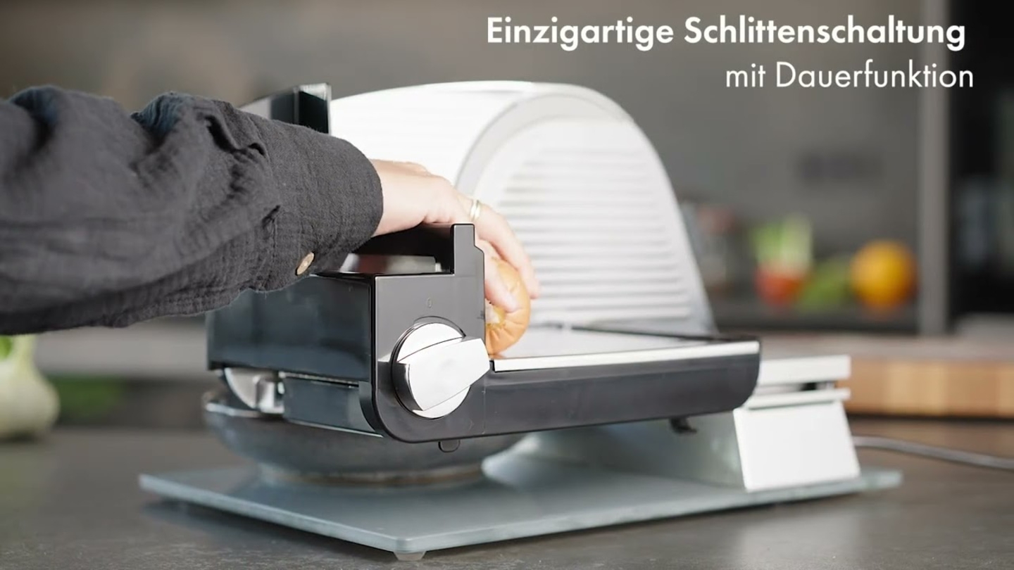 Person schneidet Brot mit einer Schneidemaschine in der Küche.