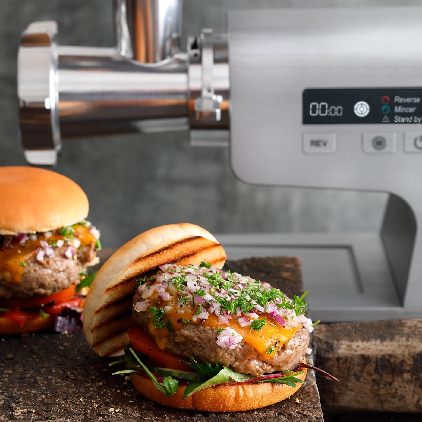 Burger mit Käse und Zwiebeln, vor einer Fleischwolfmaschine