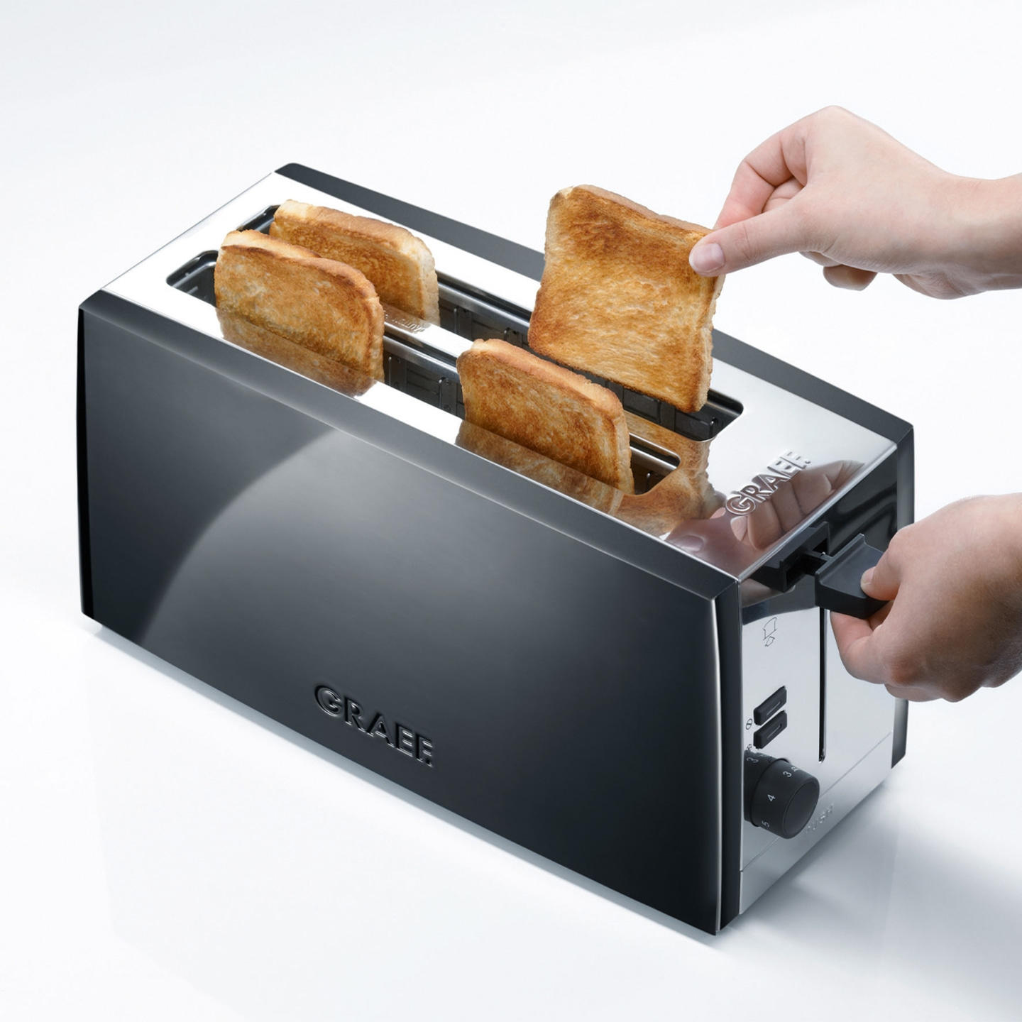 Ein Toaster mit Toast, eine Hand nimmt Toast heraus, ein Knopf ist zu sehen.