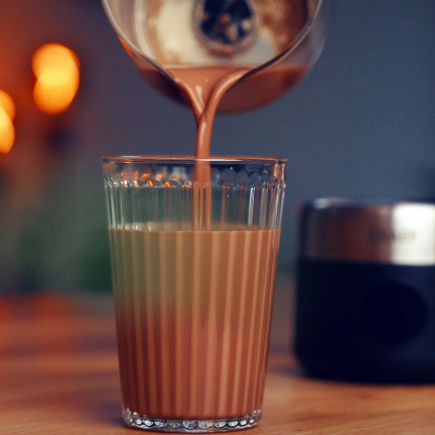 Schokolade wird in ein Glas gegossen, warmes Licht im Hintergrund.