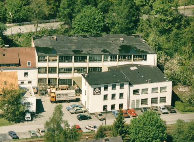 Luftaufnahme von Gebäuden mit Bäumen und geparkten Autos in der Nähe.