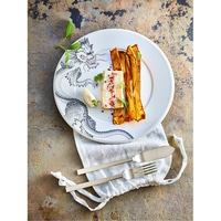 Plate of food, cutlery, napkin on stone. Delicious meal, well presented.