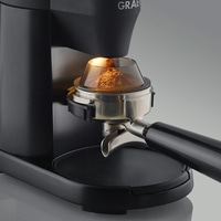 Coffee grinder with coffee powder and portafilter, close-up, black