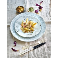 Plate of asparagus dish with cutlery and flowers on linen tablecloth