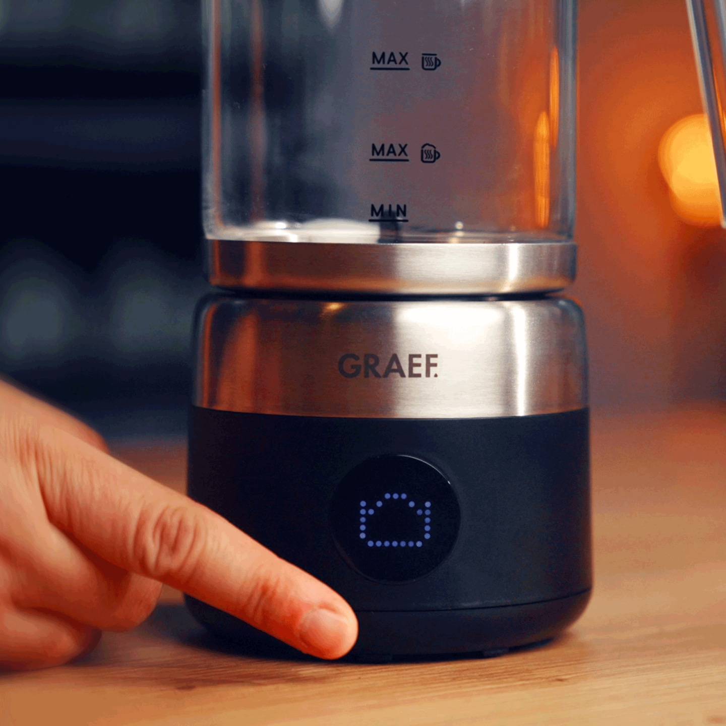 Ein Finger drückt auf die Anzeigeeinheit eines Wasserkochers von Graef.