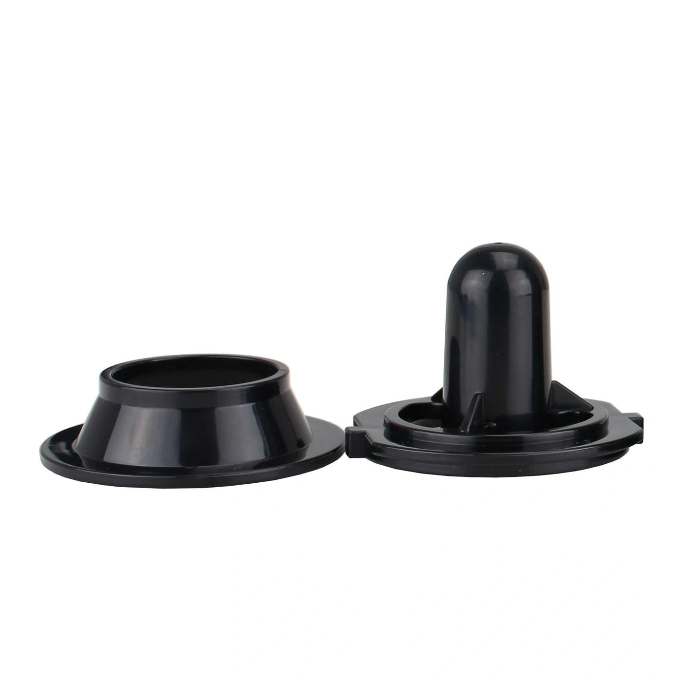 Two black plastic parts lying on a white background, close up.