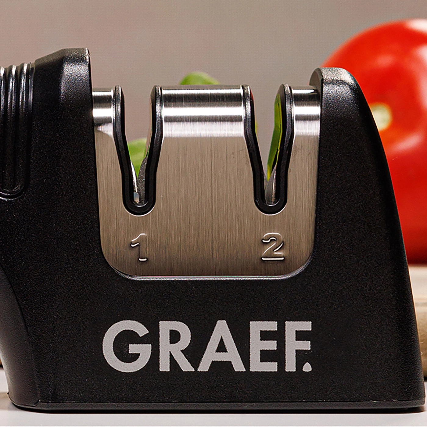 A Graef knife sharpener with numbers 1 and 2, next to a red tomato.