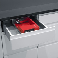 Rote Küchenmaschine in einer Schublade. Schwarze Arbeitsplatte und weiße Schränke.