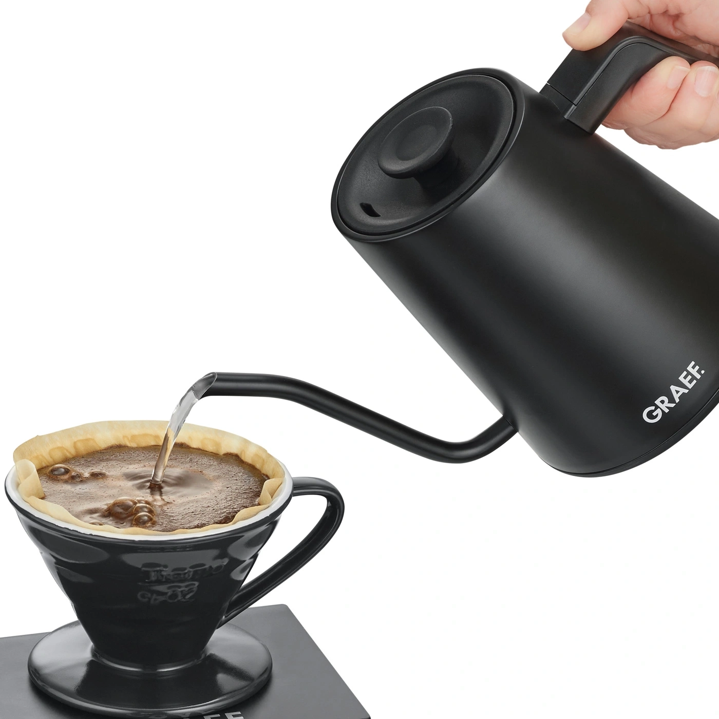Black kettle pouring coffee into a cup with filter paper.
