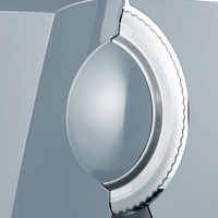Close-up of a silver serrated blade embedded in a grey surface, with a reflective dome.