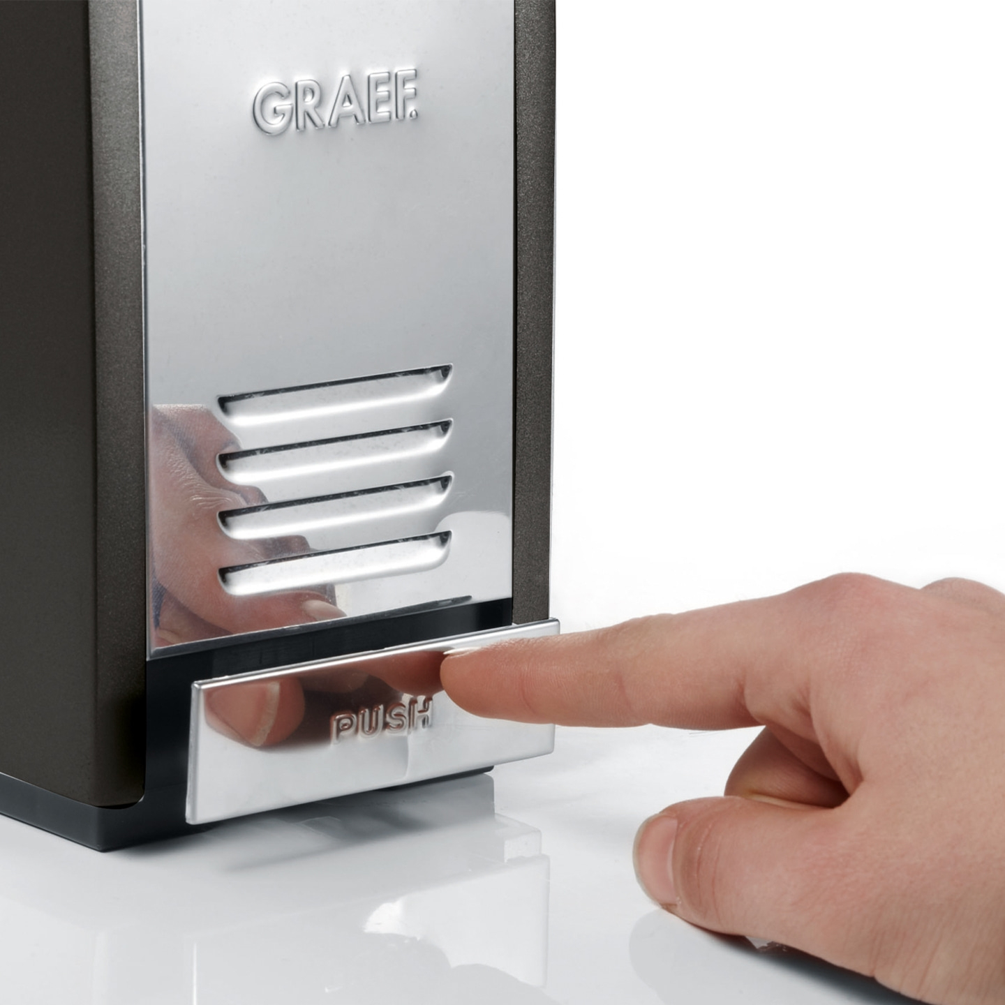 Hand drückt auf silberne Taste mit der Aufschrift "PUSH" an einem Gerät