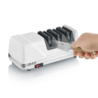 A white Graef electric knife sharpener with a knife being inserted by a hand.