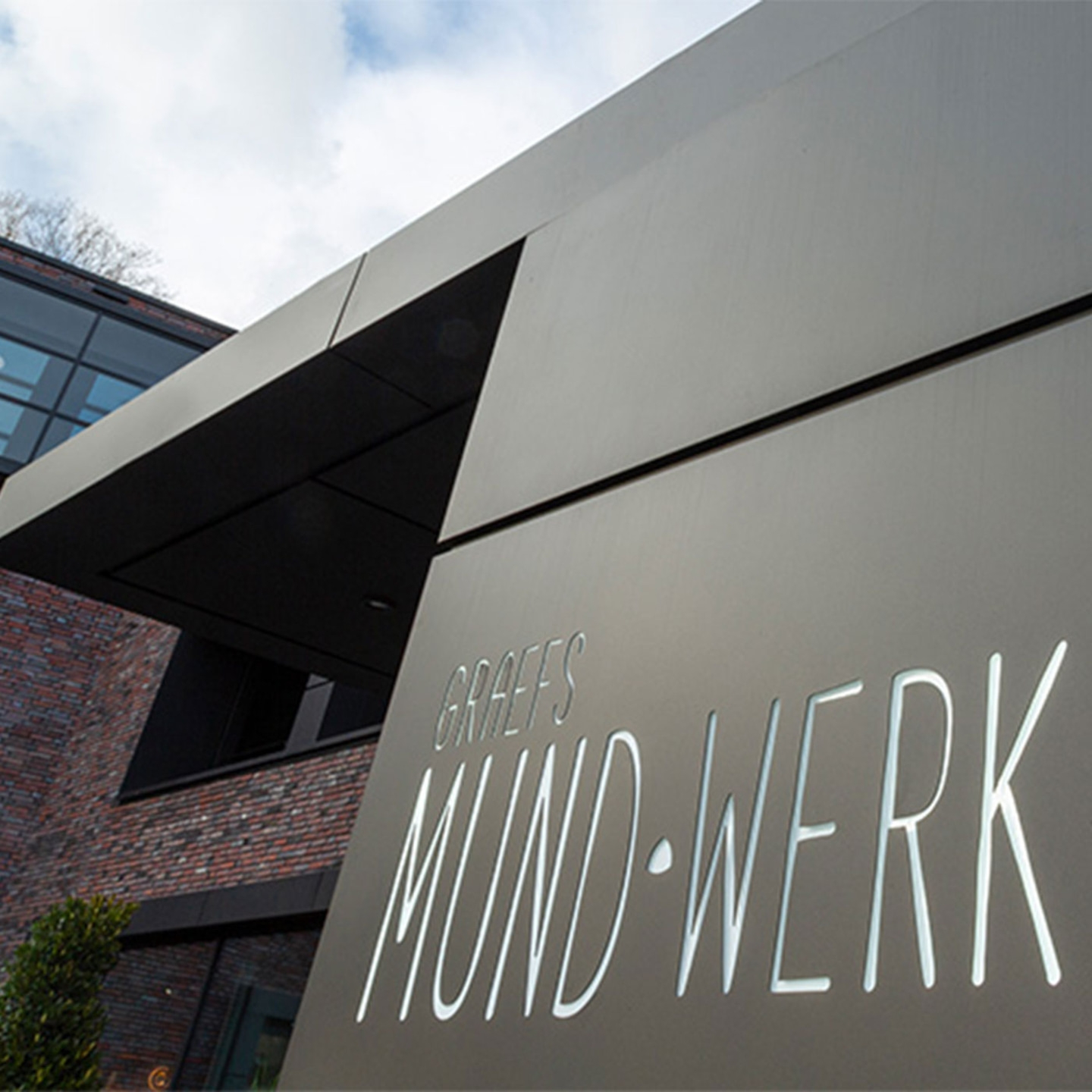 Building with 'Graefs Mund-Werk' sign, modern design, and sky background