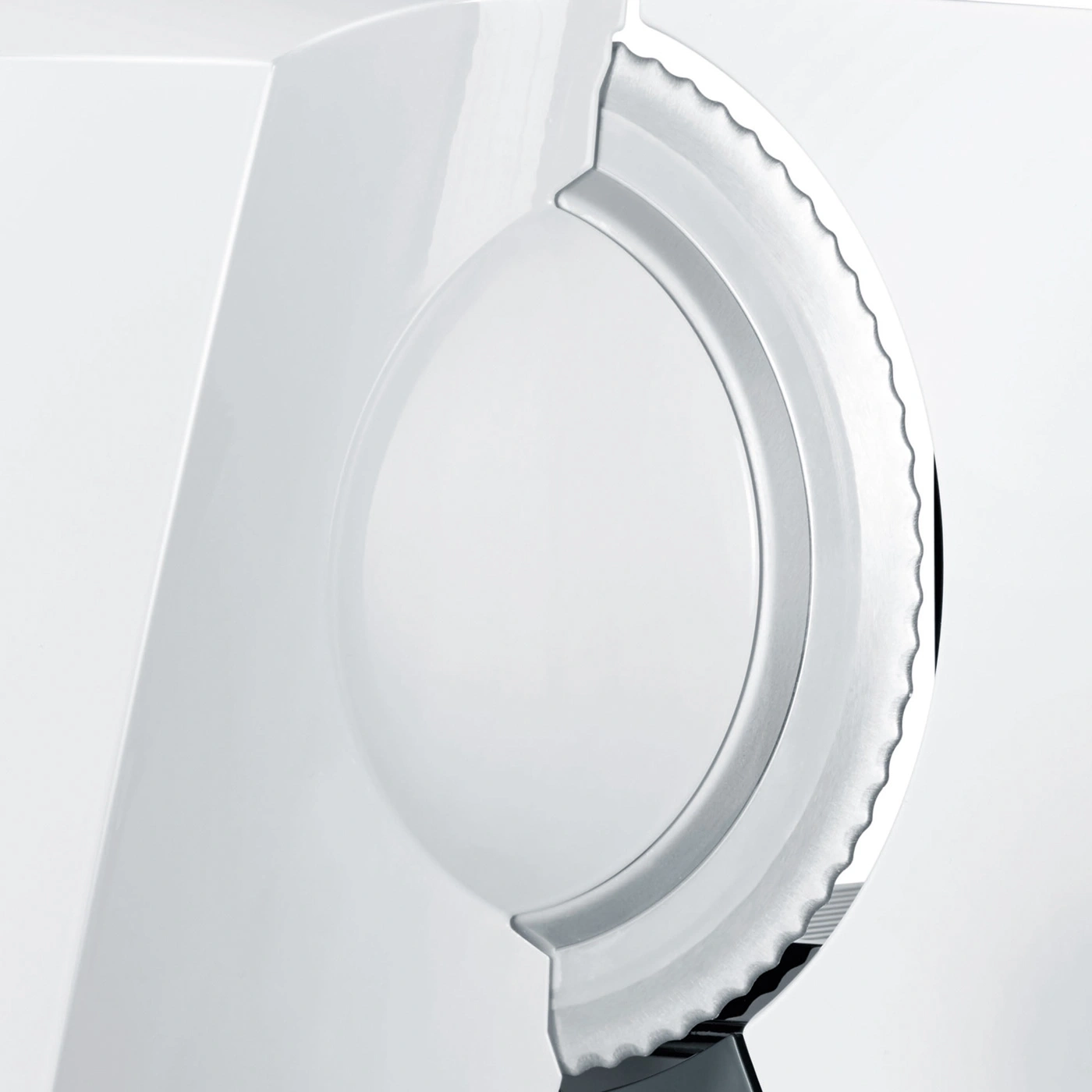 Close-up of a white appliance with a serrated metal ring.
