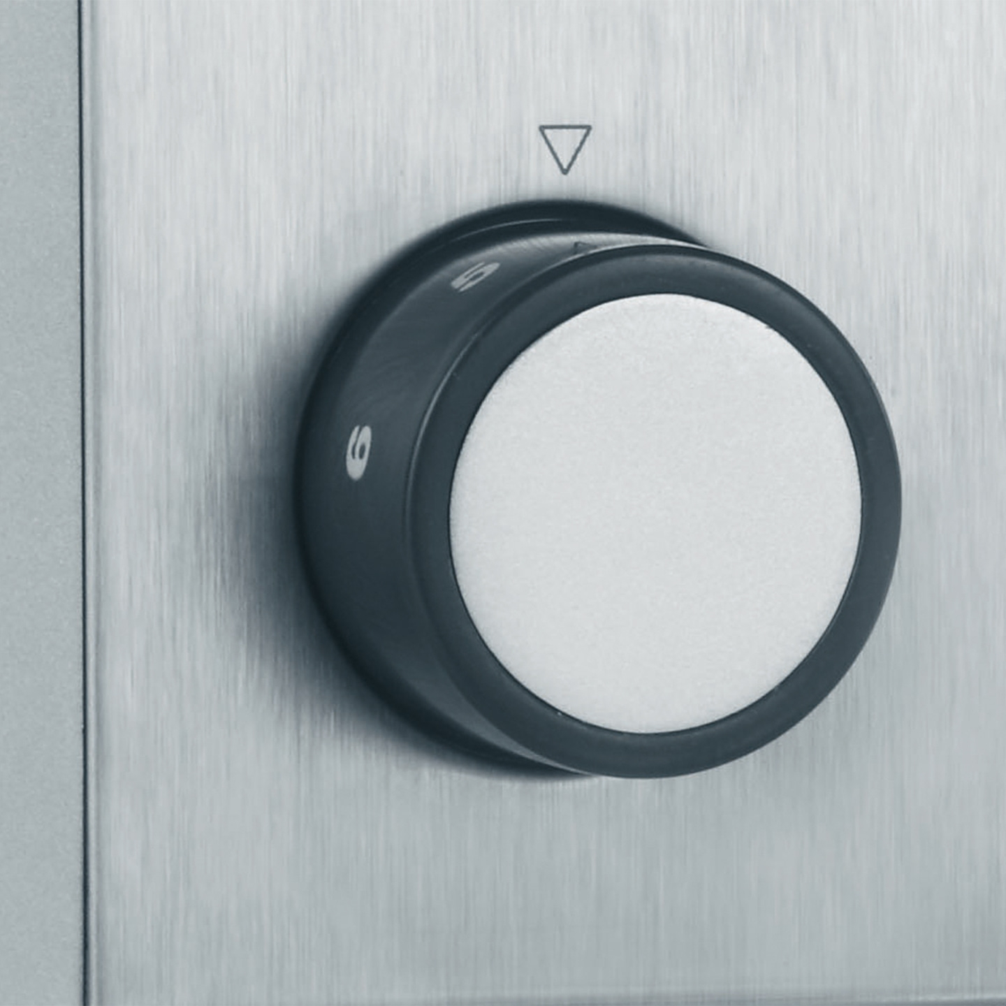 Drehknopf mit Zahlen und einem Dreieck auf einer Metalloberfläche